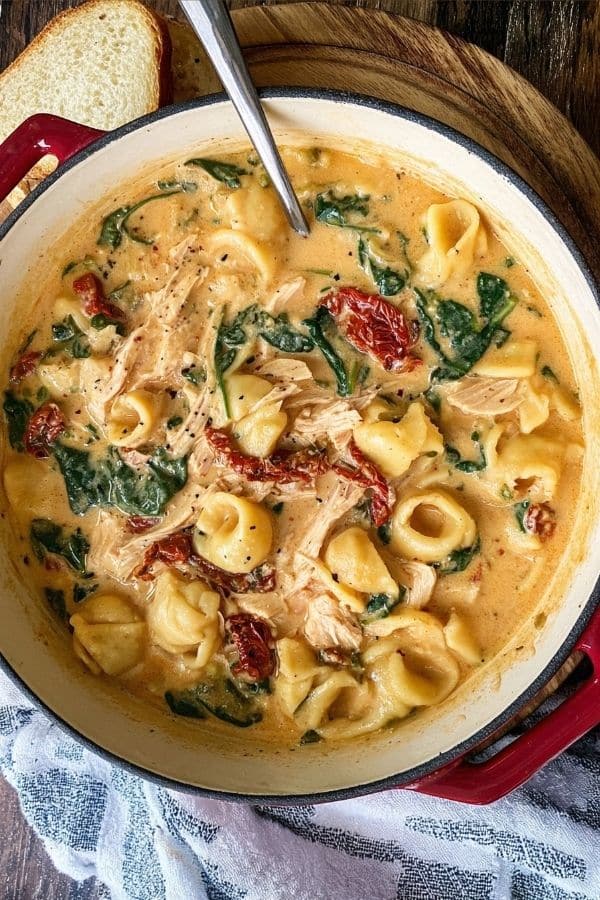 Creamy Marry Me Chicken Soup with pasta, shredded chicken, sun-dried tomatoes, and spinach in a large Dutch oven.