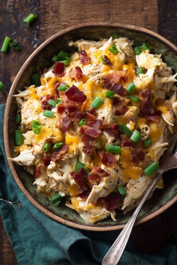 Creamy Crockpot Crack Chicken topped with bacon and cheddar in a bowl.